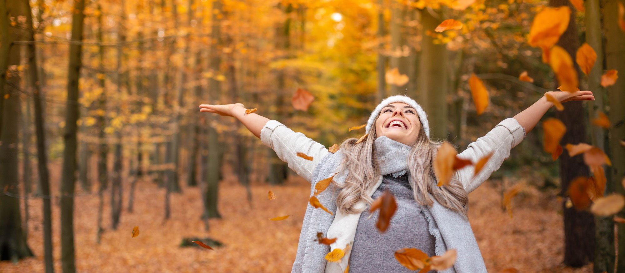 A happy woman throwing leaves in the air