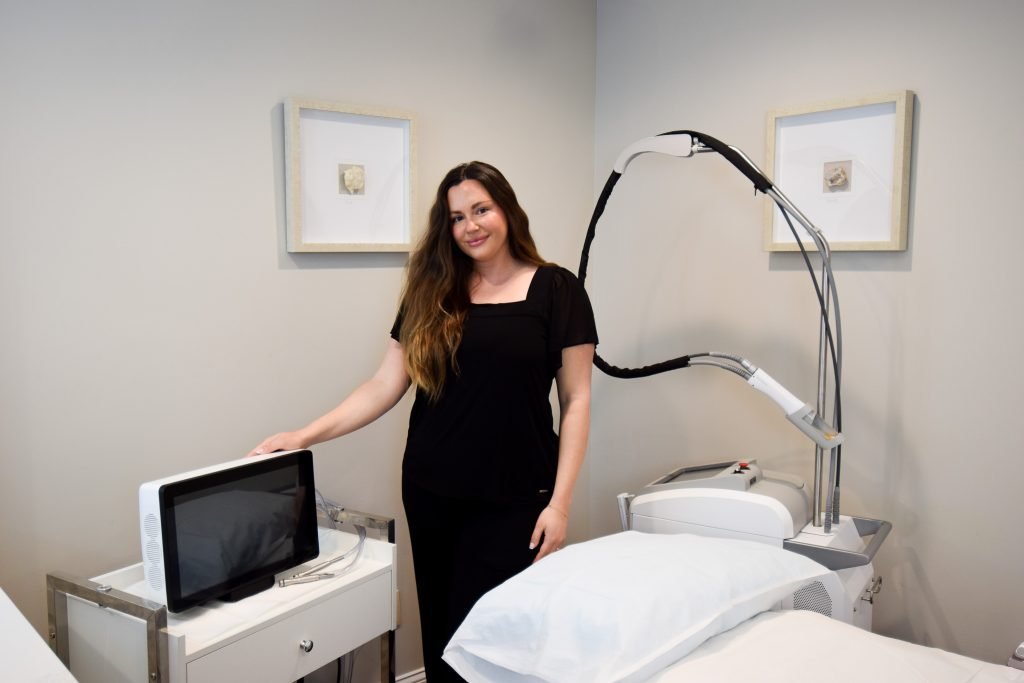 Esthetician in treatment room next to DermaSweep Microdermabrasion device